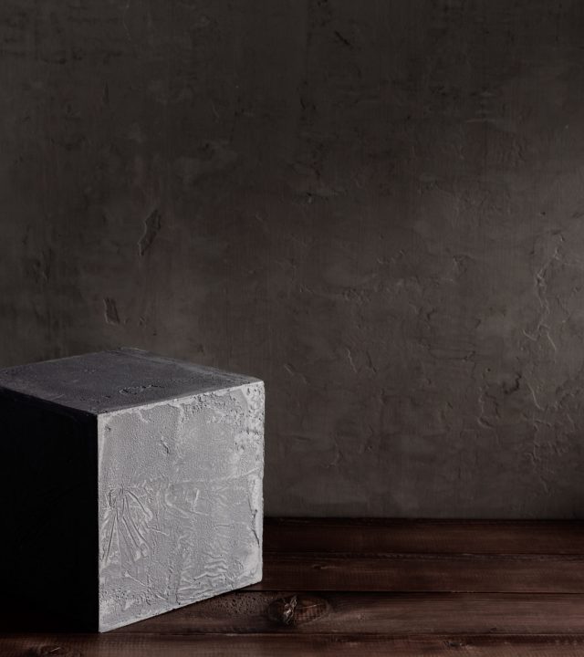 Concrete cube or brick near wall background texture. Abstract art or construction concept of minimalism design